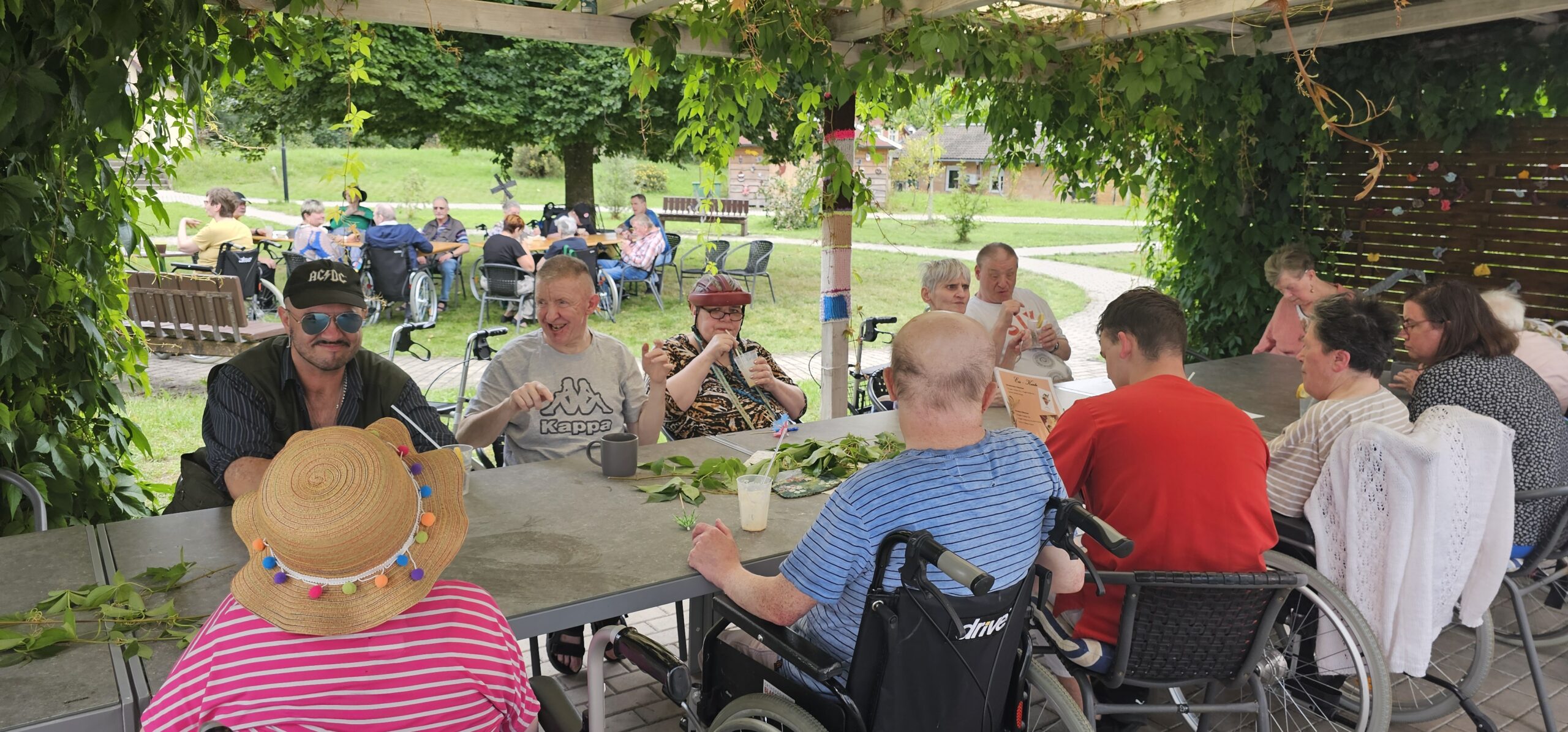 die Bewohner*innen mit ihren Angehörigen sitzen draußen im Garten