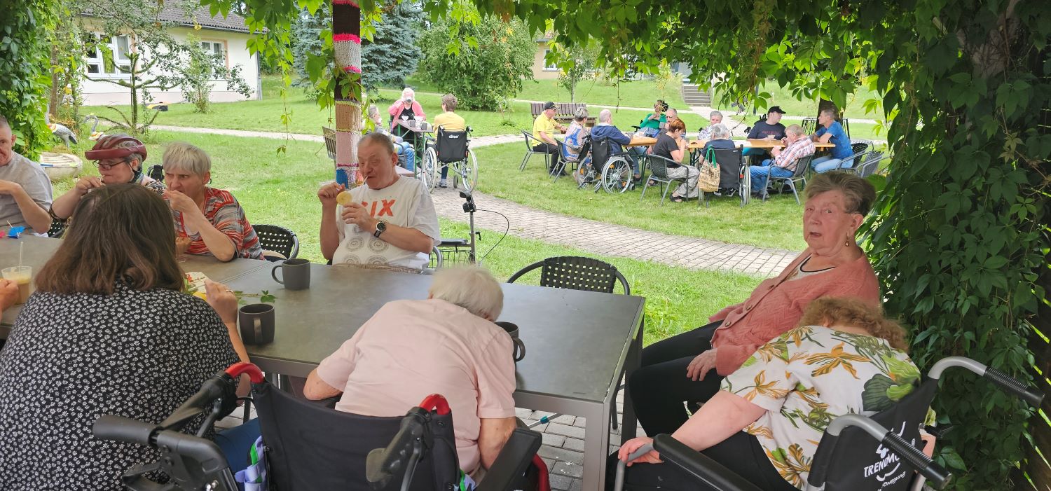 die Bewohner*innen mit ihren Angehörigen sitzen draußen im Garten