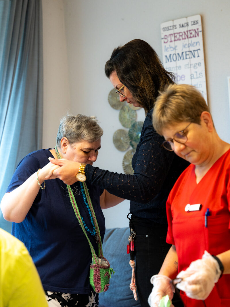 zwei Pflegerinnen helfen einer Bewohnerin