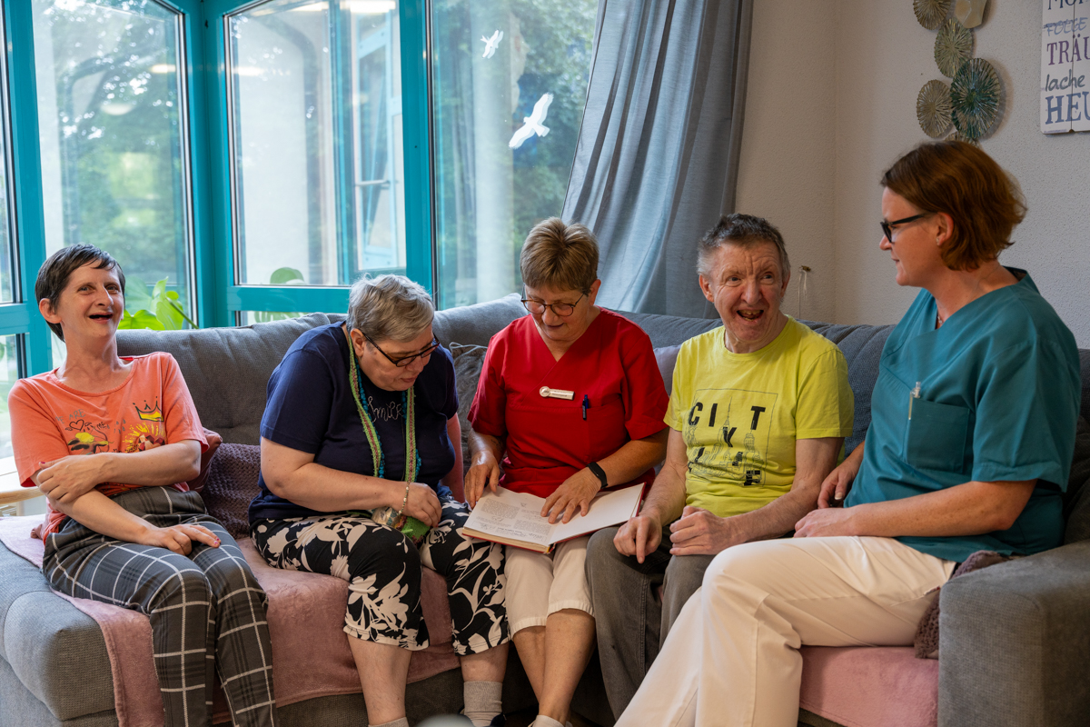 zwei Pflegerinnen lesen den Bewohner*innen etwas vor
