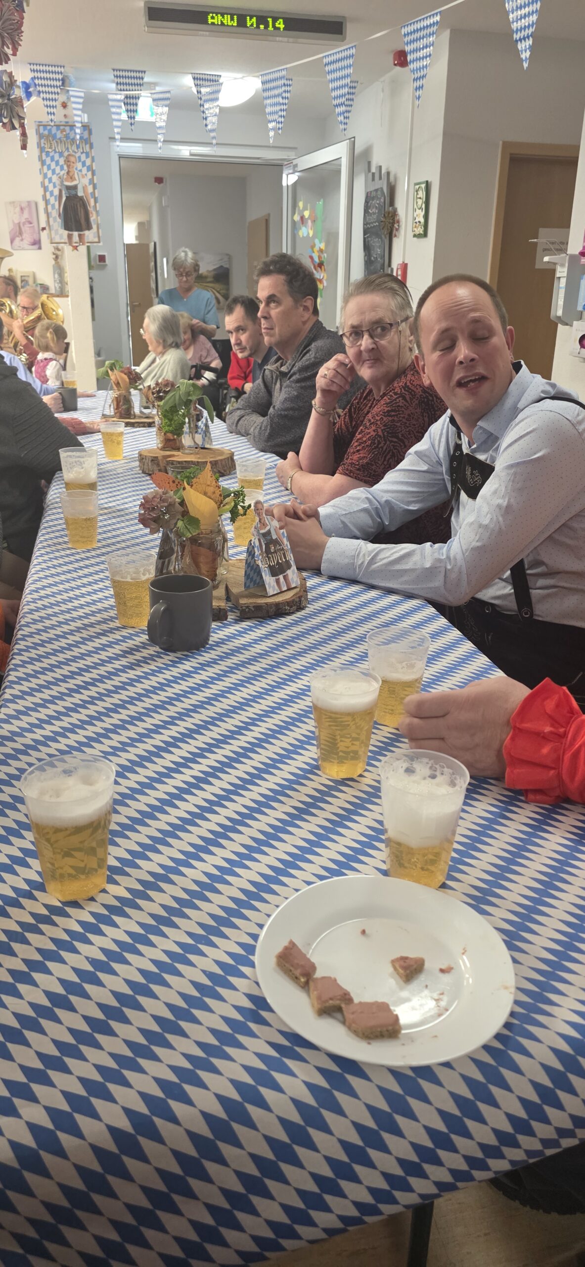 die Bewohner*innen sitzen am geschmückten Tisch und trinken Bier